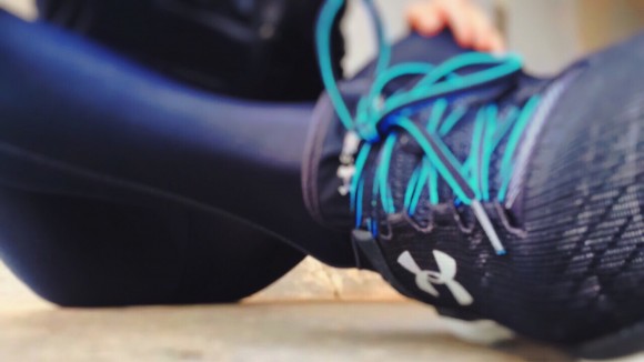 A person is sitting on the floor, she is in sportswear. The goal is focused on his right shoe, which is a running shoe.